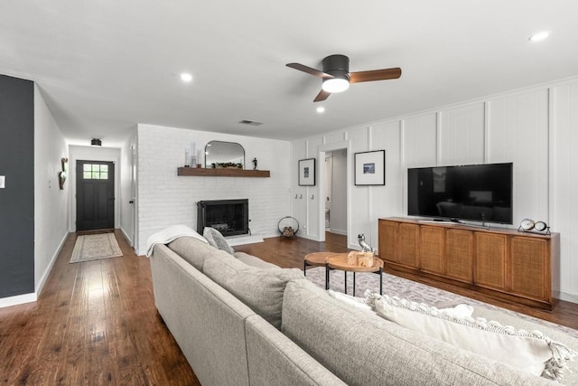 living area with a fireplace, a ceiling fan, baseboards, dark wood-type flooring, and visible vents