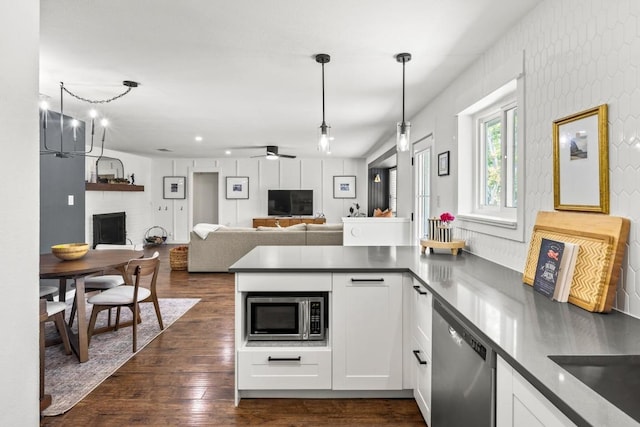 kitchen featuring a peninsula, open floor plan, stainless steel appliances, white cabinetry, and dark wood-type flooring