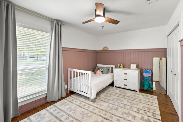 bedroom with wood finished floors, a ceiling fan, a wainscoted wall, and visible vents