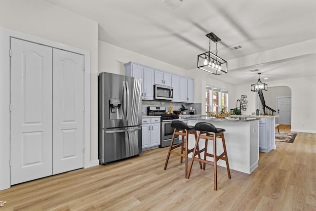 kitchen featuring a breakfast bar area, arched walkways, a center island, stainless steel appliances, and visible vents