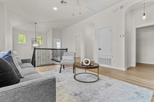 living area with visible vents, arched walkways, baseboards, and wood finished floors