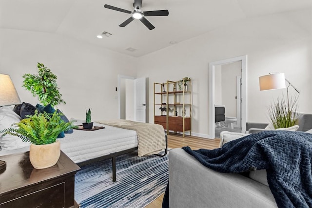 bedroom featuring connected bathroom, vaulted ceiling, light wood-style flooring, and visible vents