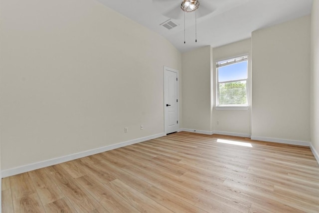 empty room with visible vents, baseboards, ceiling fan, light wood finished floors, and vaulted ceiling