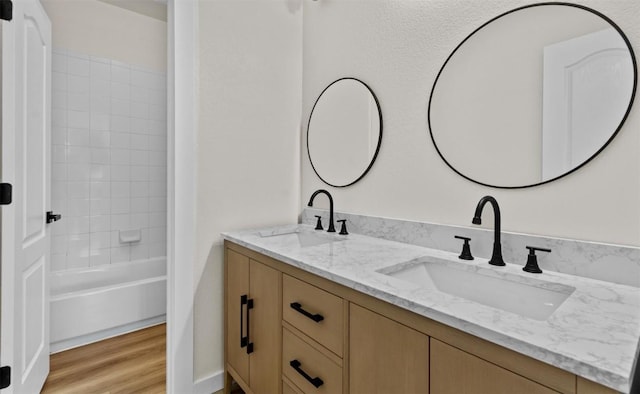 full bath featuring double vanity, a sink, and wood finished floors
