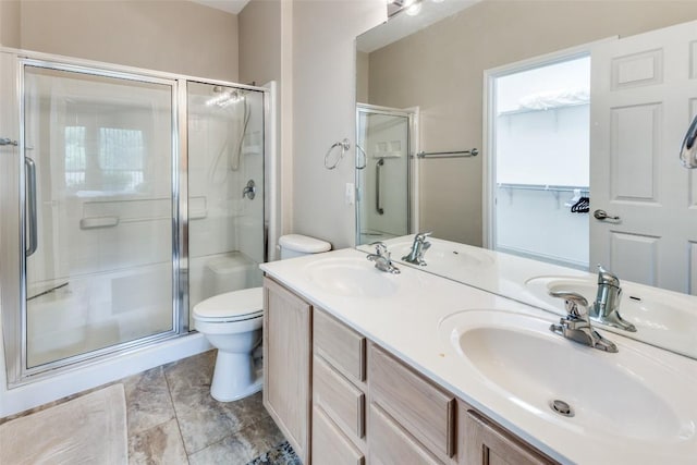 full bath featuring double vanity, toilet, a shower stall, and a sink