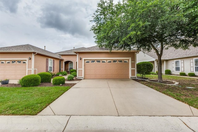 view of front of house featuring concrete driveway, an attached garage, a shingled roof, and a front lawn