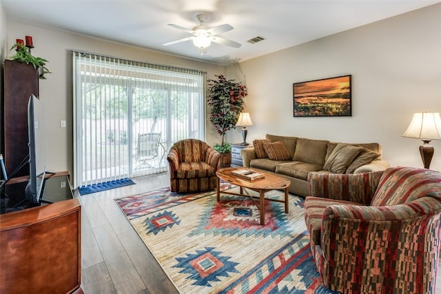 living area with a ceiling fan, wood finished floors, and visible vents