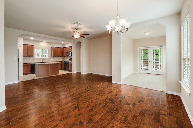 unfurnished living room with arched walkways, a sink, ceiling fan with notable chandelier, and wood finished floors