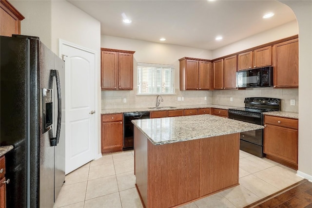 kitchen featuring a sink, tasteful backsplash, a kitchen island, and black appliances