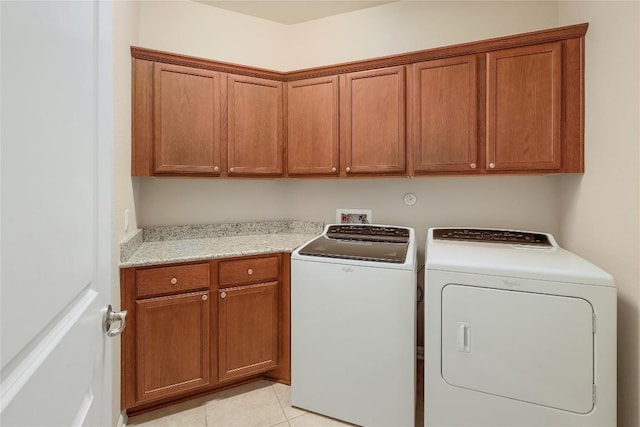 laundry area featuring light tile patterned floors, cabinet space, and washing machine and clothes dryer