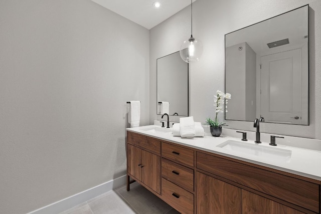 bathroom featuring double vanity, baseboards, a sink, and tile patterned flooring