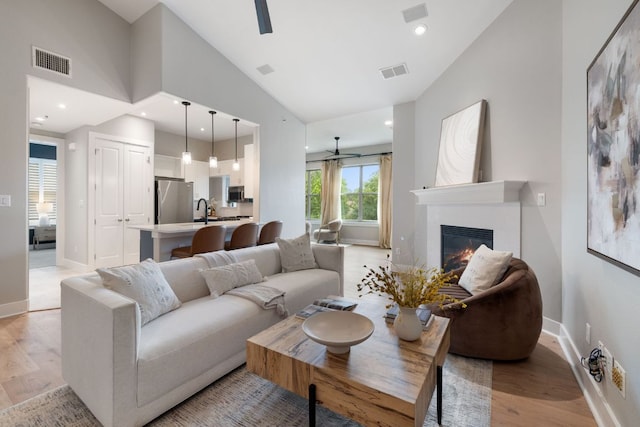 living room featuring visible vents, light wood finished floors, and ceiling fan