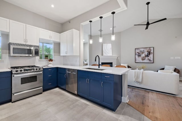 kitchen featuring a sink, stainless steel appliances, open floor plan, a peninsula, and blue cabinets