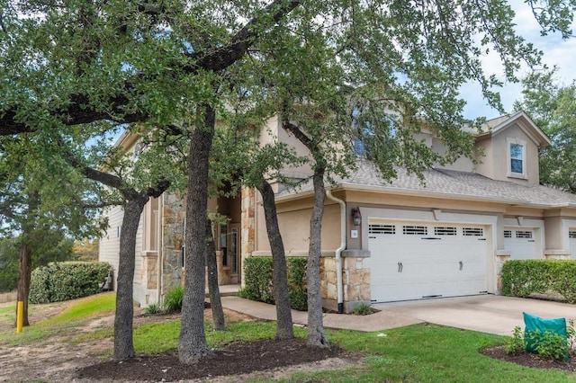 view of front of home featuring an attached garage, stucco siding, concrete driveway, and stone siding