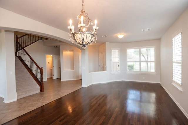 unfurnished dining area with arched walkways, baseboards, stairs, and wood finished floors