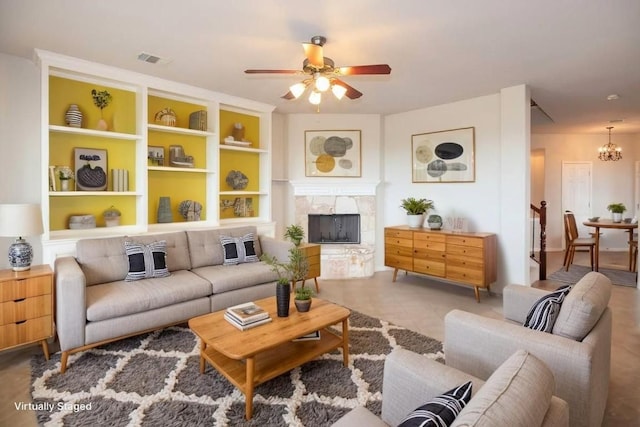 living room featuring visible vents, ceiling fan with notable chandelier, and a tile fireplace