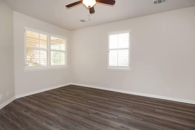unfurnished room with baseboards, ceiling fan, dark wood-style floors, and visible vents