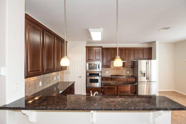 kitchen featuring dark stone countertops, a peninsula, backsplash, and stainless steel appliances