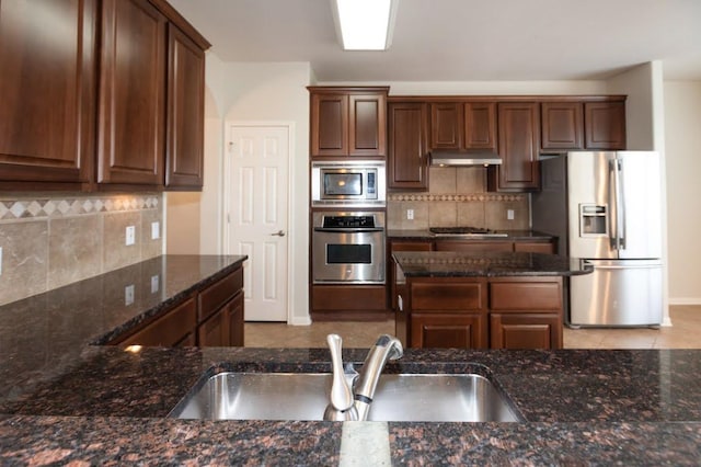 7901 SW Pkwy Unit 16, Austin, TX 78735 - kitchen with appliances with stainless steel finishes, under cabinet range hood, dark stone countertops, and tasteful backsplash