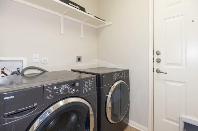 washroom featuring separate washer and dryer, laundry area, and baseboards