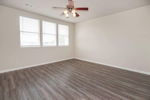 unfurnished room featuring dark wood-style flooring, baseboards, visible vents, and a ceiling fan