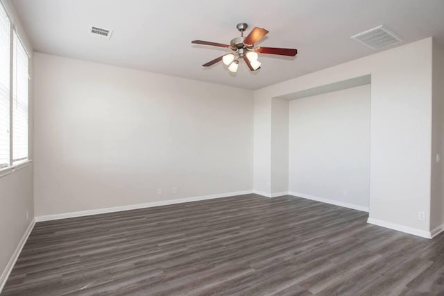 unfurnished room with visible vents, a ceiling fan, baseboards, and dark wood-type flooring