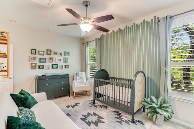 bedroom with ceiling fan, a crib, carpet, attic access, and baseboards