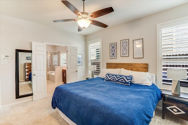 carpeted bedroom with ensuite bathroom, baseboards, and ceiling fan