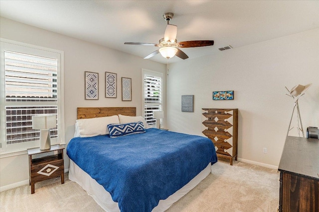 bedroom featuring visible vents, a ceiling fan, baseboards, and light carpet