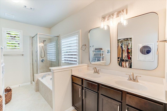 full bath with visible vents, a sink, double vanity, and a shower stall
