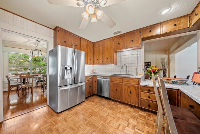 kitchen with appliances with stainless steel finishes, brown cabinetry, a sink, and visible vents