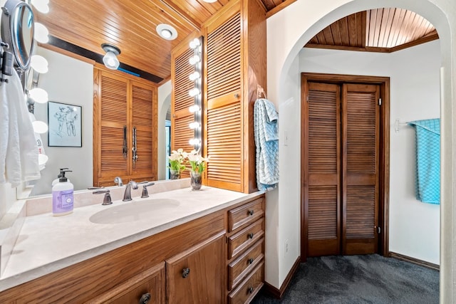 bathroom with vanity, baseboards, wood ceiling, and a closet