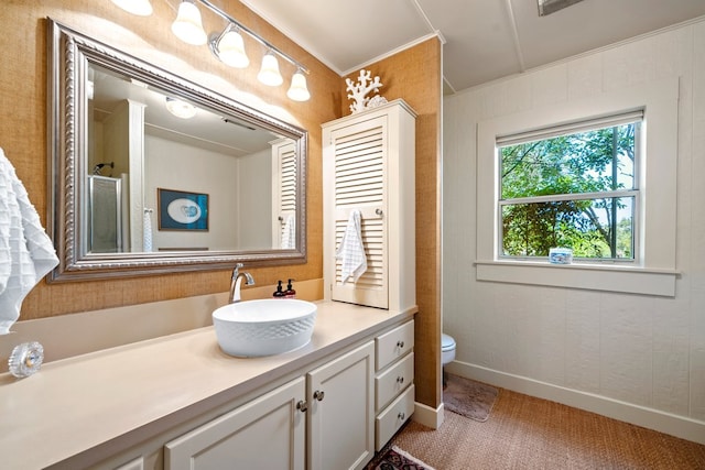 bathroom with vanity, toilet, baseboards, a shower, and ornamental molding