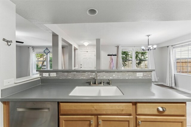 kitchen with a sink, dishwasher, a chandelier, and hanging light fixtures
