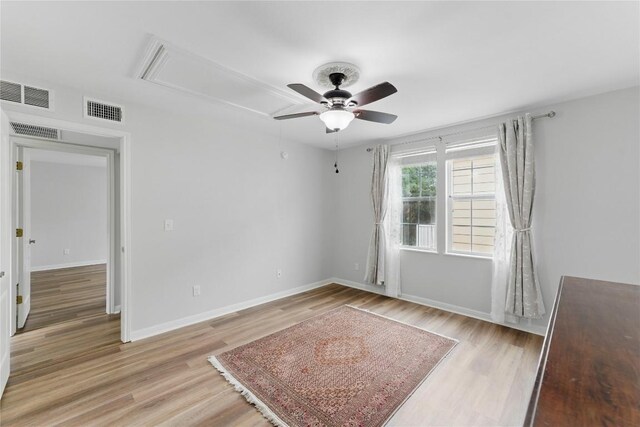 spare room featuring a ceiling fan, visible vents, attic access, and light wood-type flooring