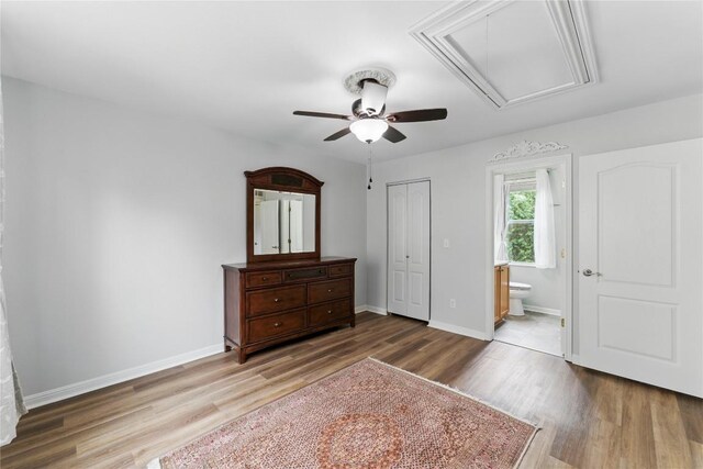 bedroom with a closet, wood finished floors, baseboards, attic access, and connected bathroom