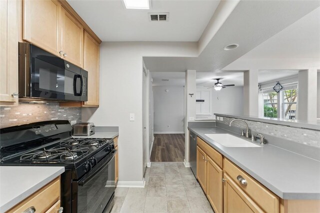 kitchen featuring a ceiling fan, decorative backsplash, a sink, and black appliances