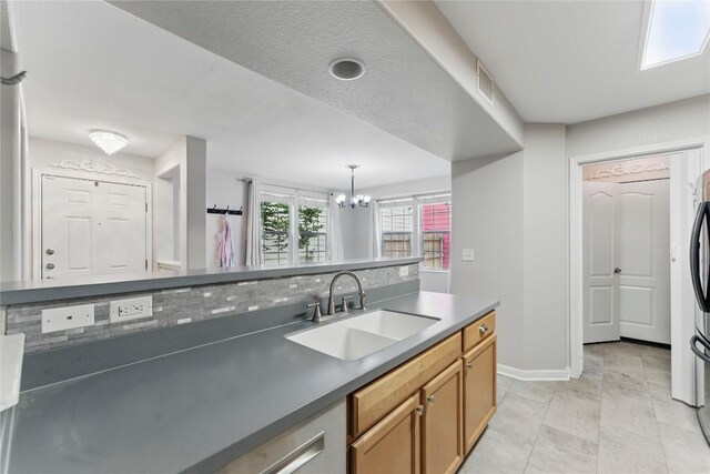 kitchen with an inviting chandelier, visible vents, baseboards, a sink, and hanging light fixtures