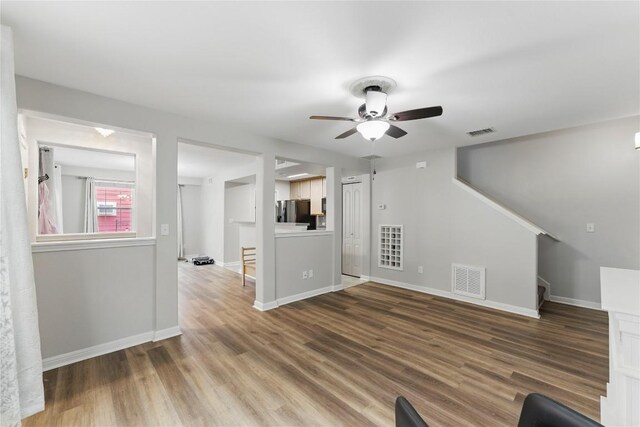 unfurnished living room with baseboards, ceiling fan, wood finished floors, and visible vents