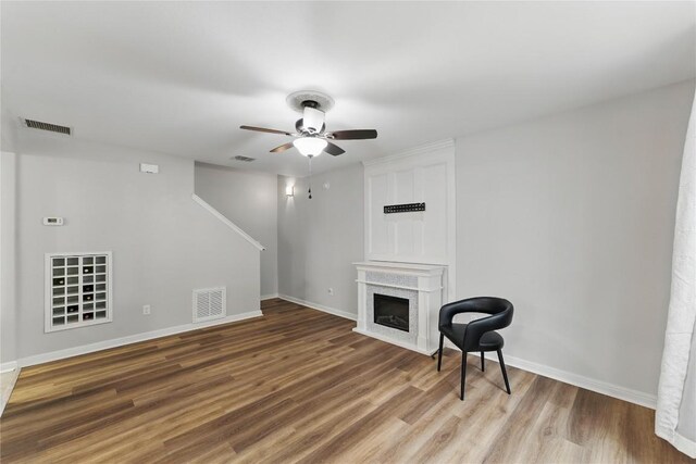 unfurnished living room with ceiling fan, baseboards, visible vents, and wood finished floors