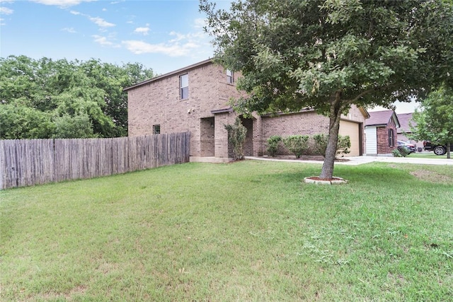 view of front of home featuring brick siding, fence, a front yard, and a garage
