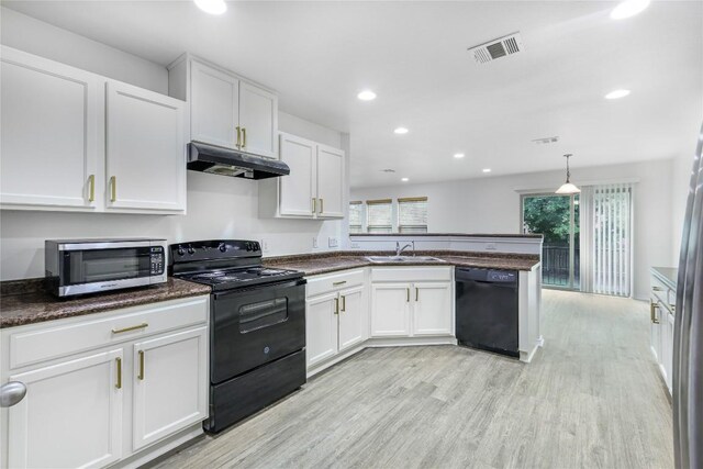 kitchen with a sink, black appliances, a peninsula, under cabinet range hood, and a wealth of natural light