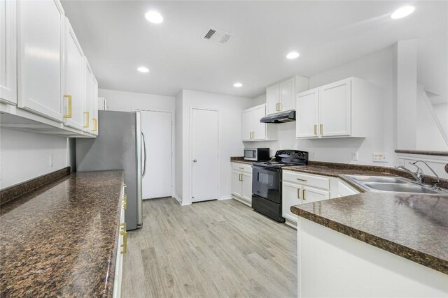 kitchen with dark countertops, appliances with stainless steel finishes, a sink, under cabinet range hood, and visible vents
