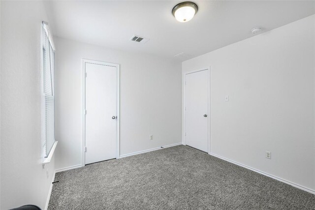 unfurnished bedroom with carpet flooring, baseboards, and visible vents