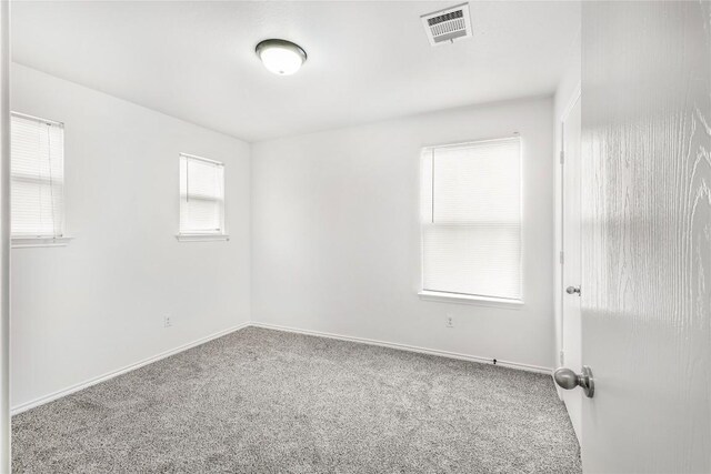 spare room featuring visible vents, carpet flooring, and baseboards