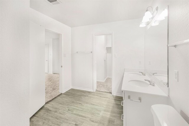 full bathroom featuring a sink, double vanity, wood finished floors, and visible vents
