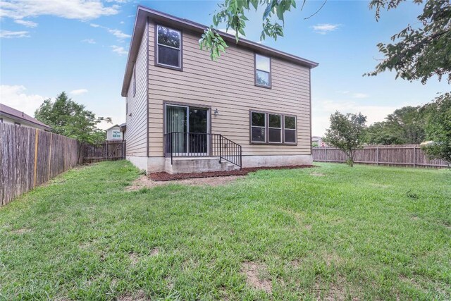 rear view of property with a fenced backyard and a yard