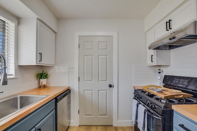 kitchen with a sink, dishwasher, a healthy amount of sunlight, under cabinet range hood, and black gas range