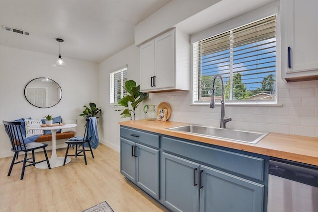 502 Tilbury Ln, Austin, TX 78745 - kitchen featuring dishwasher, backsplash, light wood-style floors, decorative light fixtures, and plenty of natural light