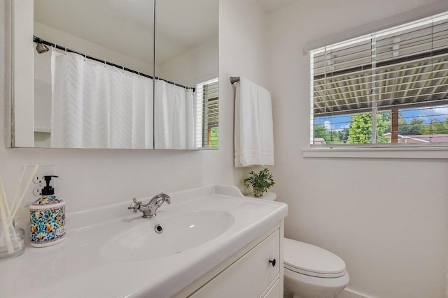 bathroom with toilet, a shower with curtain, a wealth of natural light, and vanity